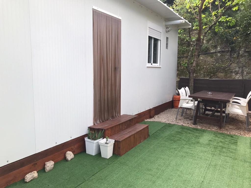 Terraza lateral con césped artificial y mesa exterior